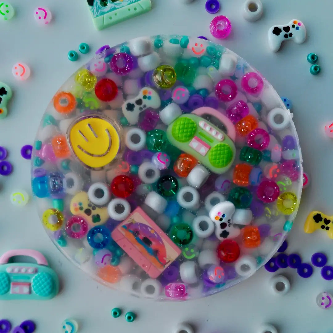 Retro Pick-Me Pad – overhead view of colorful sensory pad with pony beads, smiley faces, game controllers, boombox and cassette tape charms